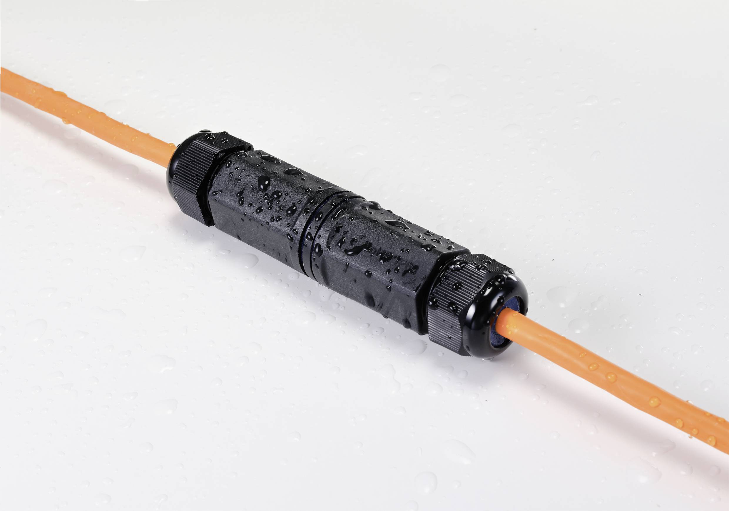 Black waterproof cable connector joining two orange cables, covered with water droplets.