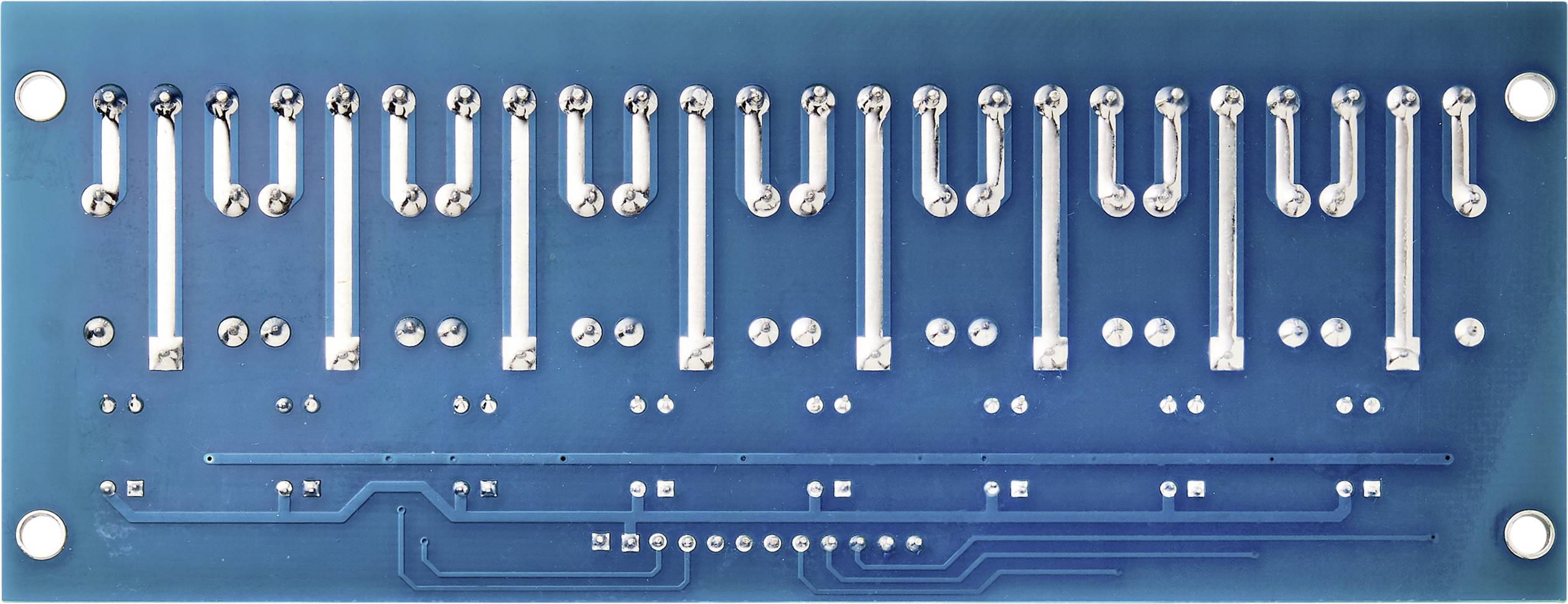 Underside of a blue printed circuit board with soldered connections and circuit traces. Silver metallic contacts are visible.