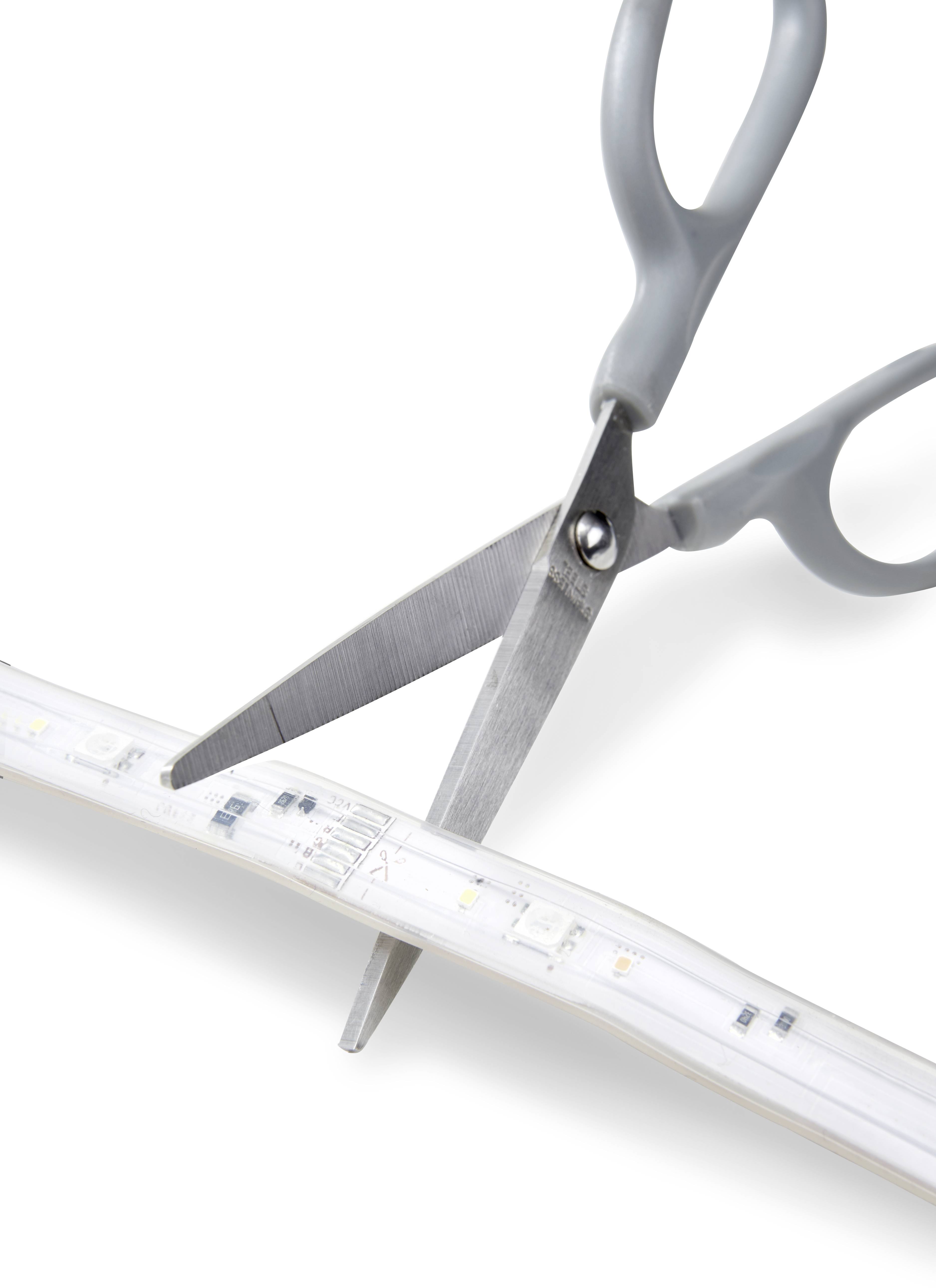 A pair of scissors cuts an LED light strip.