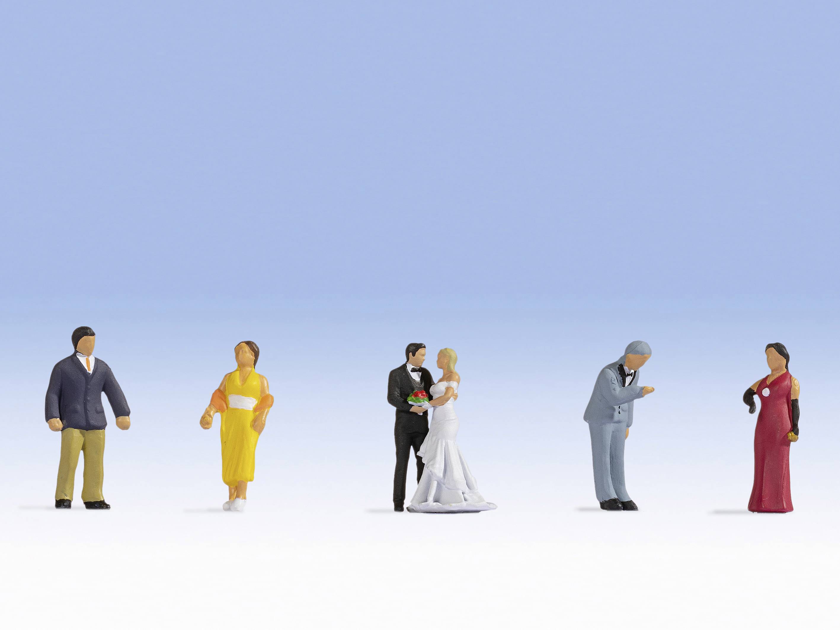 Several miniature figurines in various coloured outfits are standing on a white surface against a blue background.