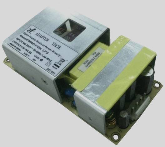 An open power supply with visible electronic components on a circuit board, including capacitors and transformer.