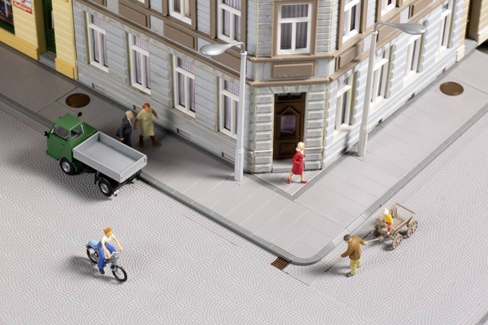 A miniature town: People are walking on the pavement, a man is cycling, and a lorry is parked on a street corner.