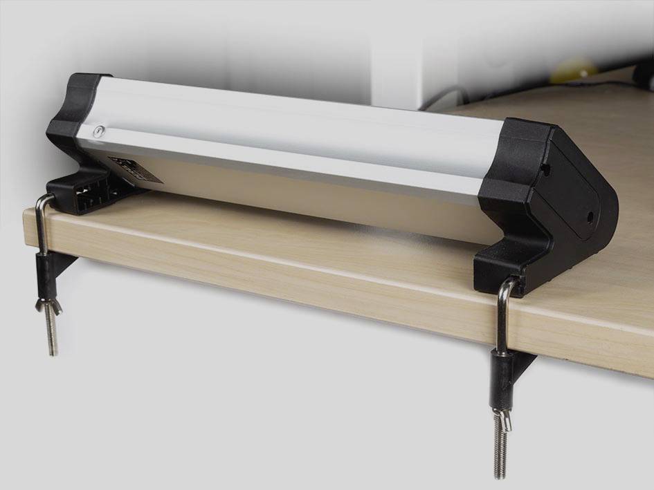 A LED lamp, which is secured with clips to a tabletop, provides overhead workplace lighting.