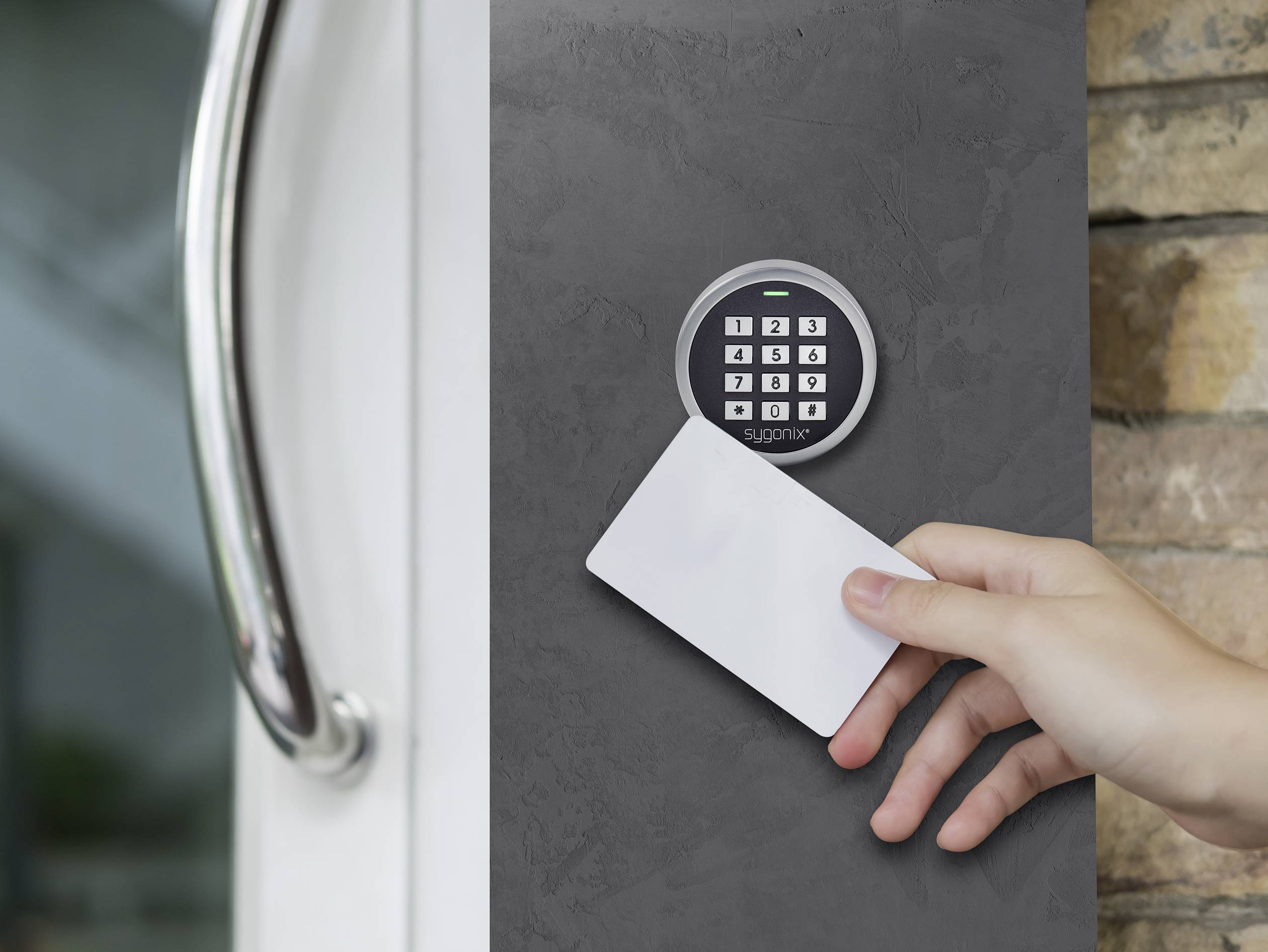 A hand is holding a white access card in front of an electronic door system with a keypad for access control.