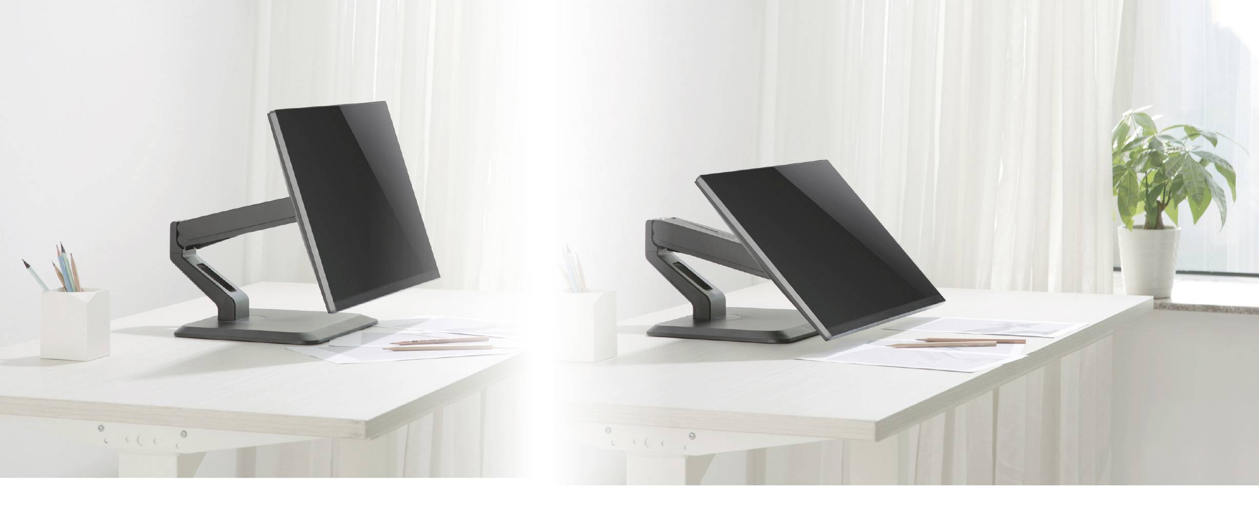 Two monitors on adjacent desks, one in an upright position, the other at an angle. A window in the background.
