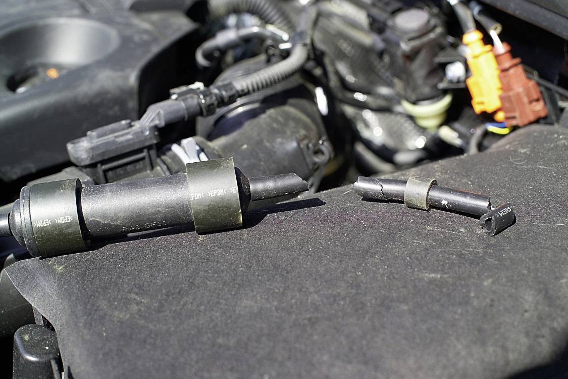 Faulty ignition coils placed on an engine cover, with visible parts of the engine in the background.