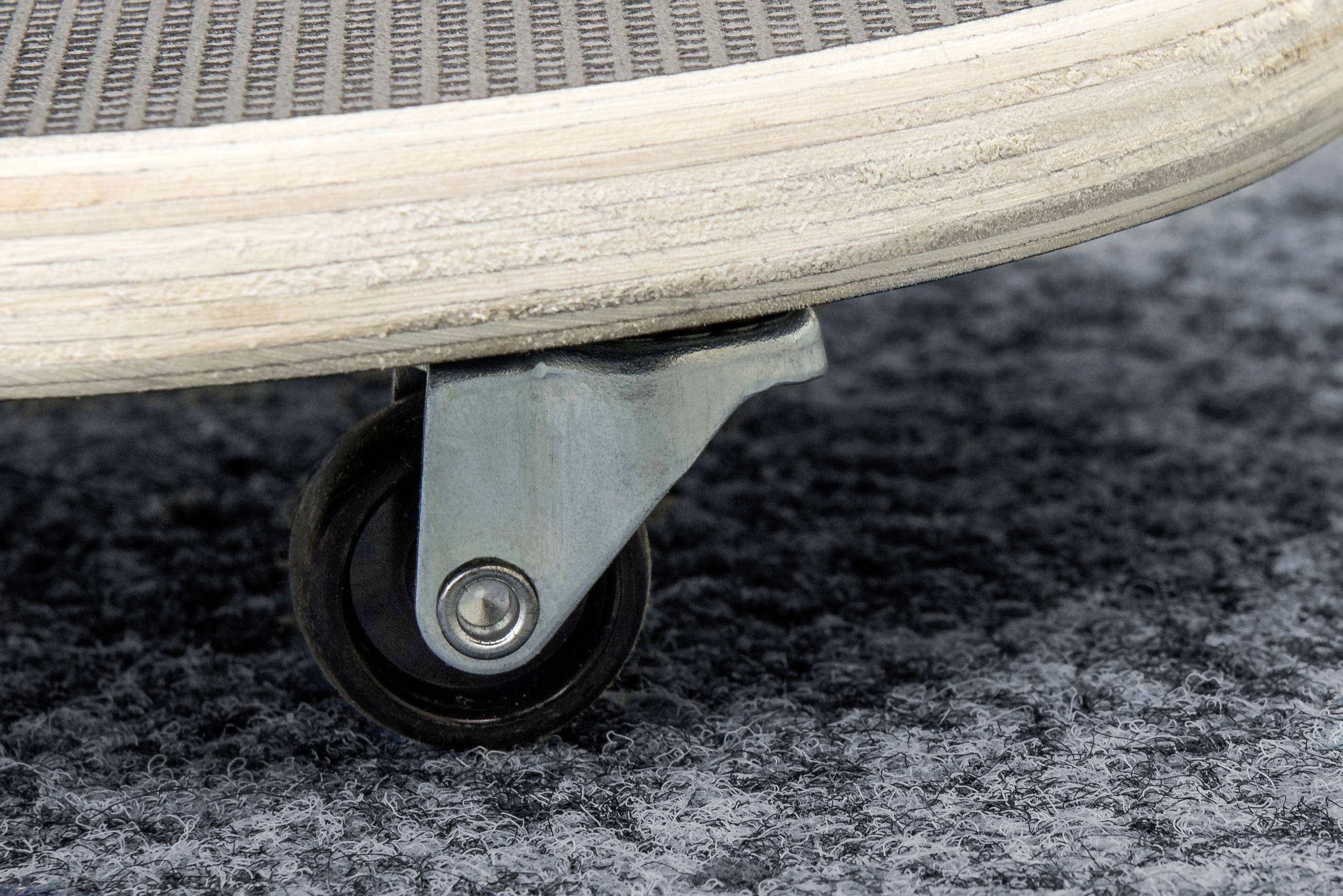 Close-up of a skateboard with a small, black wheel on grey carpet.