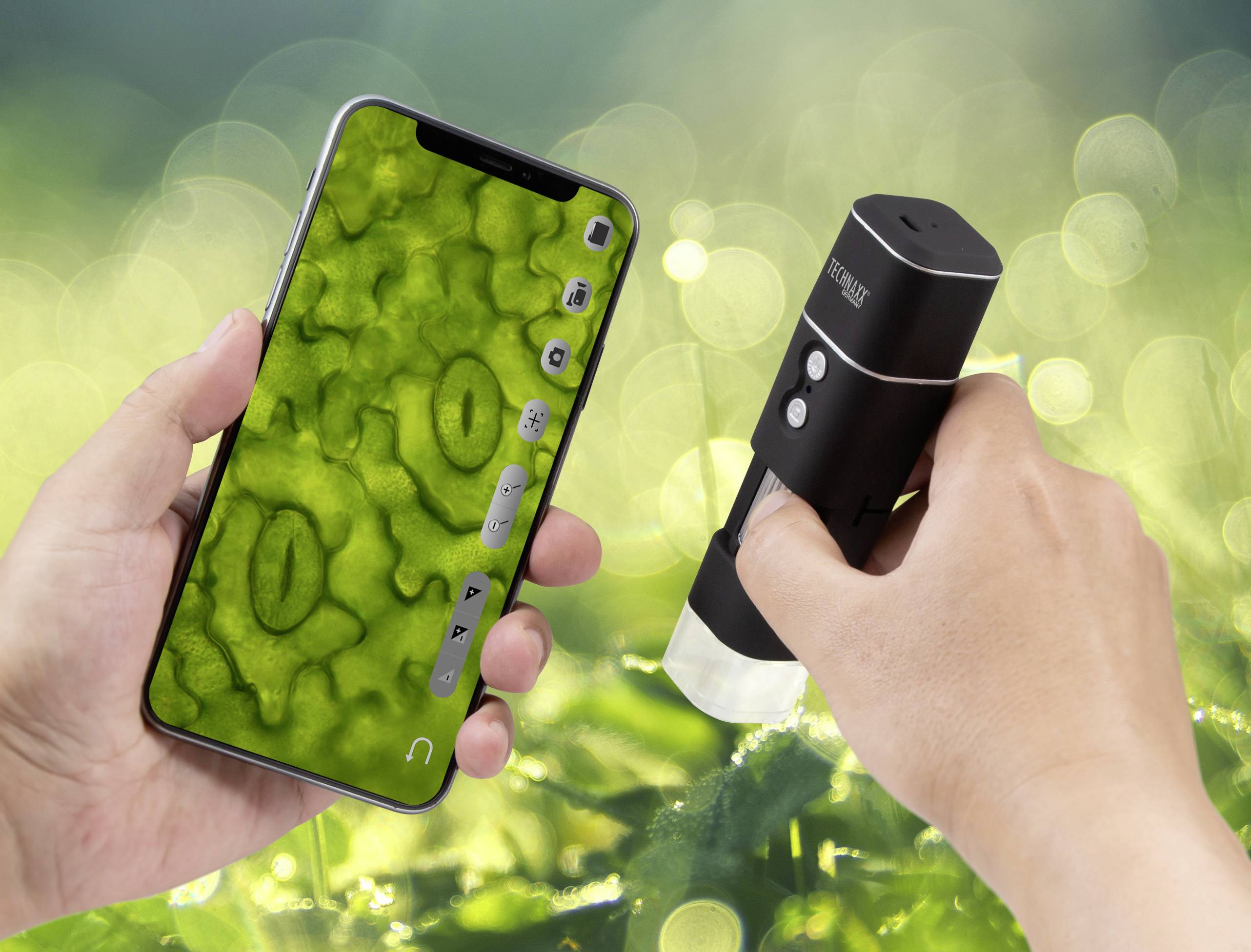 A person is holding a smartphone and a digital microscope. On the screen, an enlarged close-up of leaf cells is visible.
