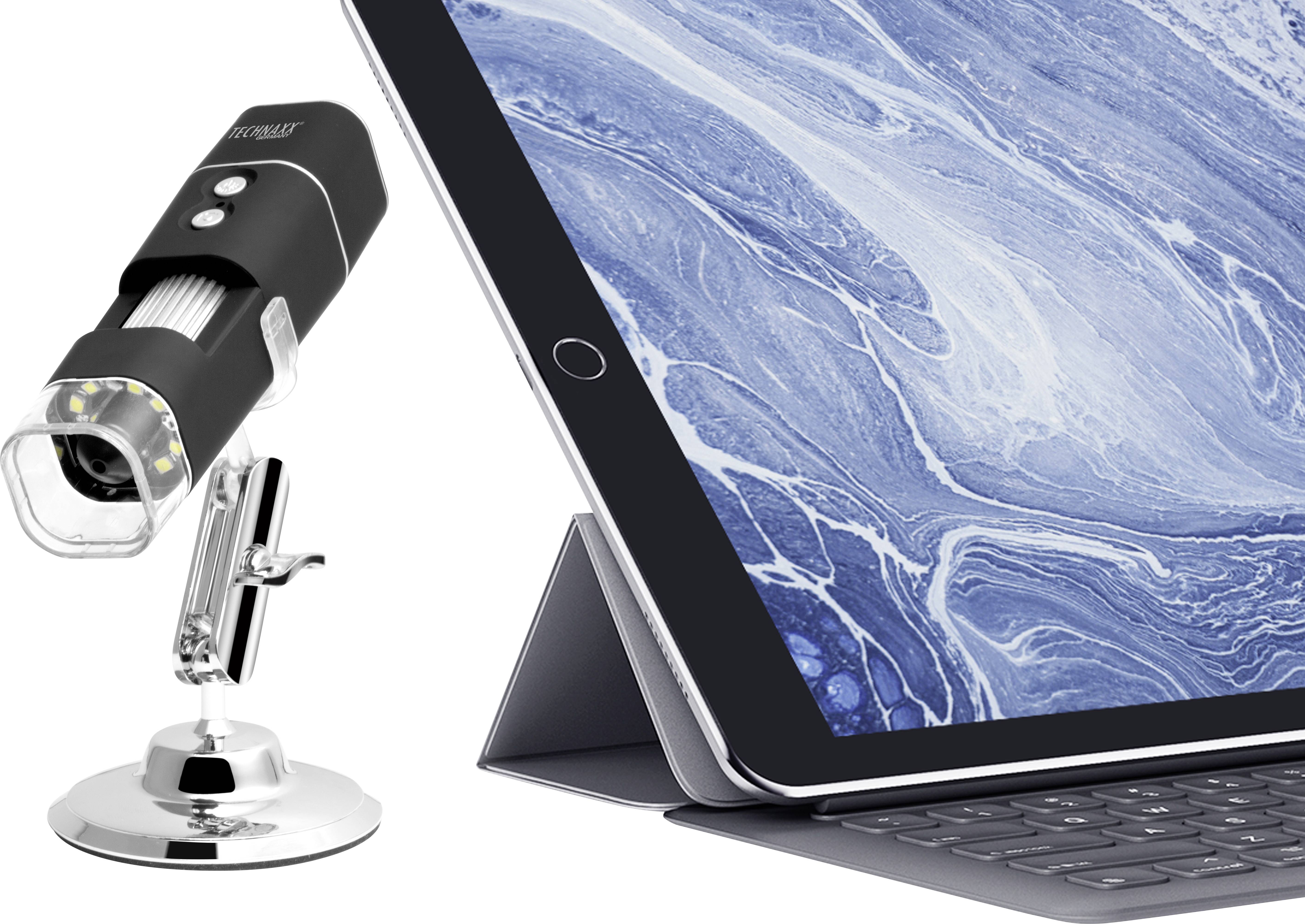 A digital microscope beside a tablet with a keyboard, displaying a close-up of a blue, marbled pattern.