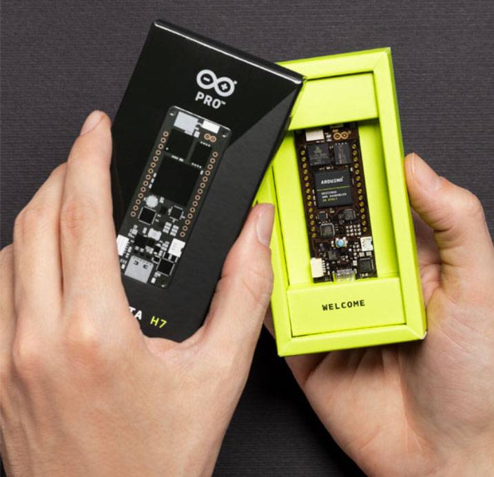 A person is holding a package and removing an Arduino board on which 'Welcome' is written.
