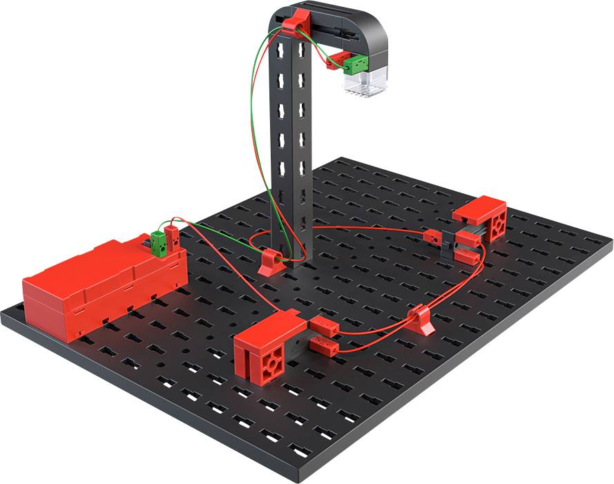 Electrical experiment kit with red and green cables on a black perforated board. Includes battery holder and electrical connectors.