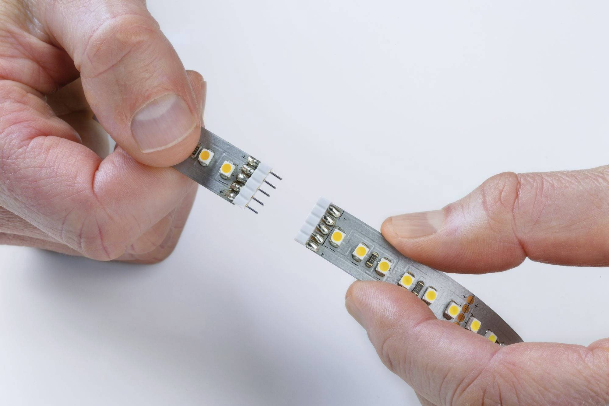 Two hands connect LED strips via a plug connector.
