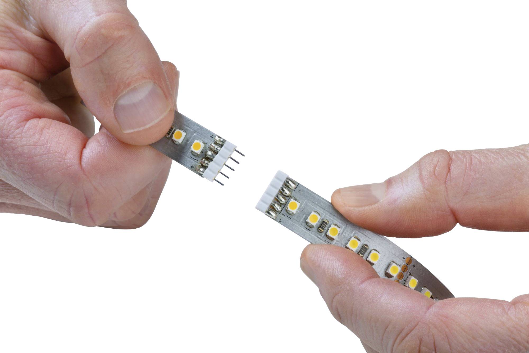 Two hands are connecting a flexible LED light strip via a connector. The strip contains multiple illuminating diodes.