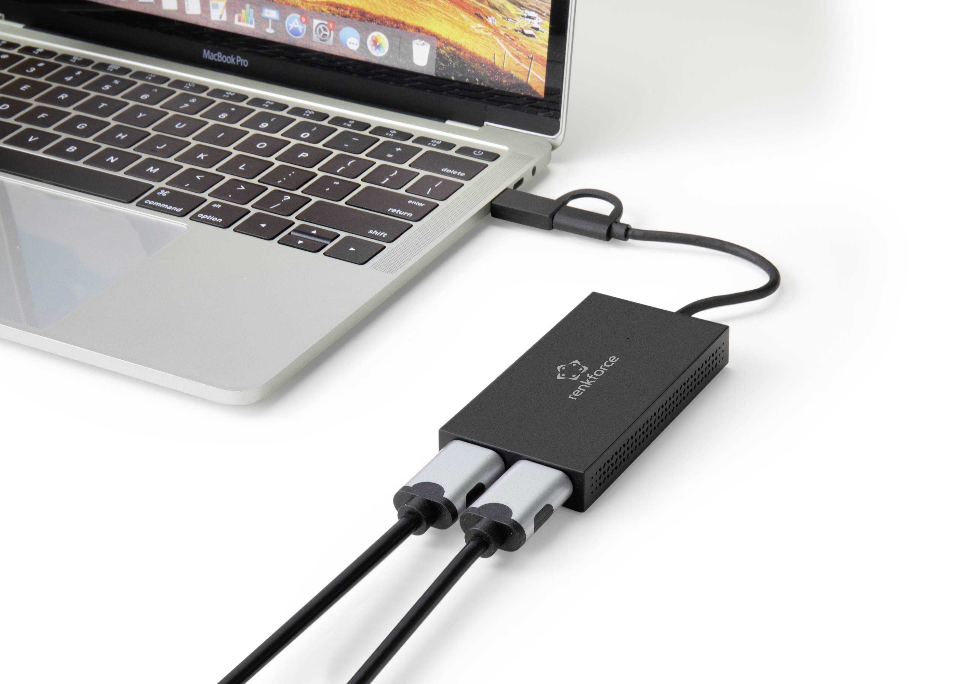 A laptop is connected to a black adapter that connects two cables. The adapter facilitates the connection of external devices.