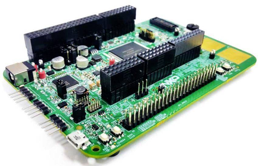 A green circuit board with electronic components, including chipsets, pins, and connectors, lies on a white background.