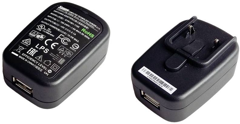 Two black USB wall chargers with technical labels and symbols on the top surface, both featuring retractable plug pins.