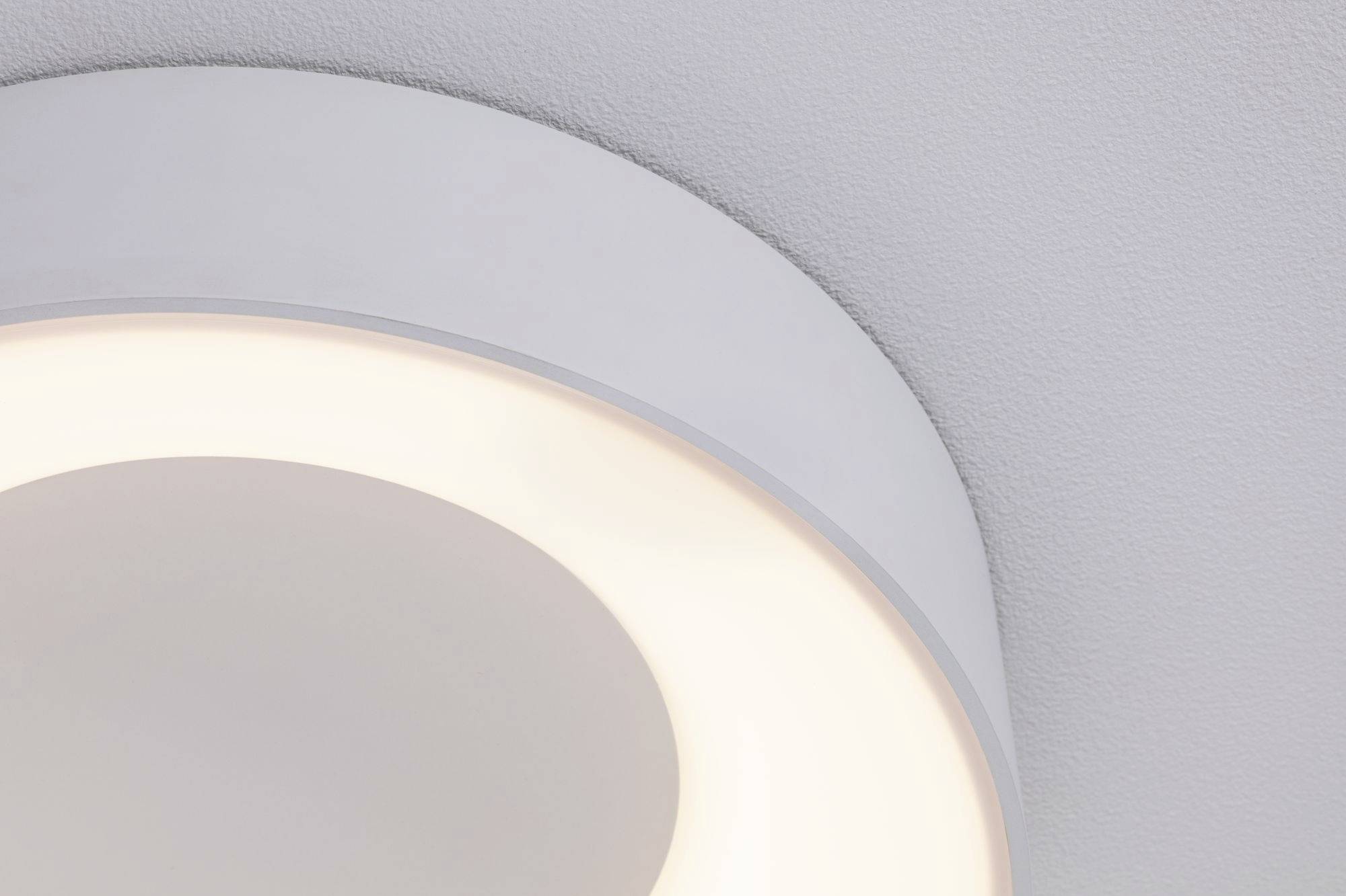 A round, modern ceiling light emits soft, warm light and is mounted on a grey ceiling.