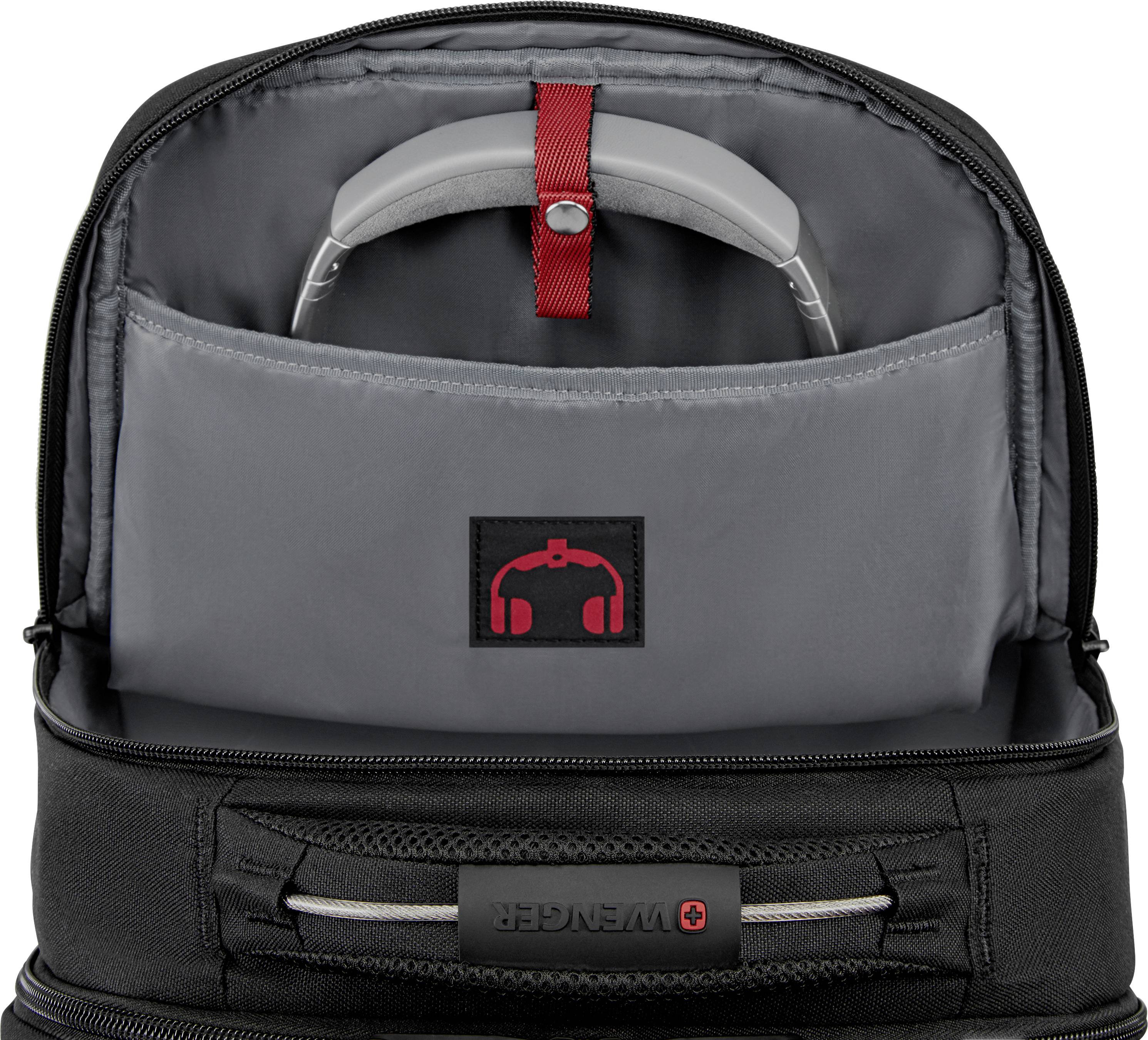 Open black rucksack shows lower compartment with grey inner pocket for headphones, red strap for securing.