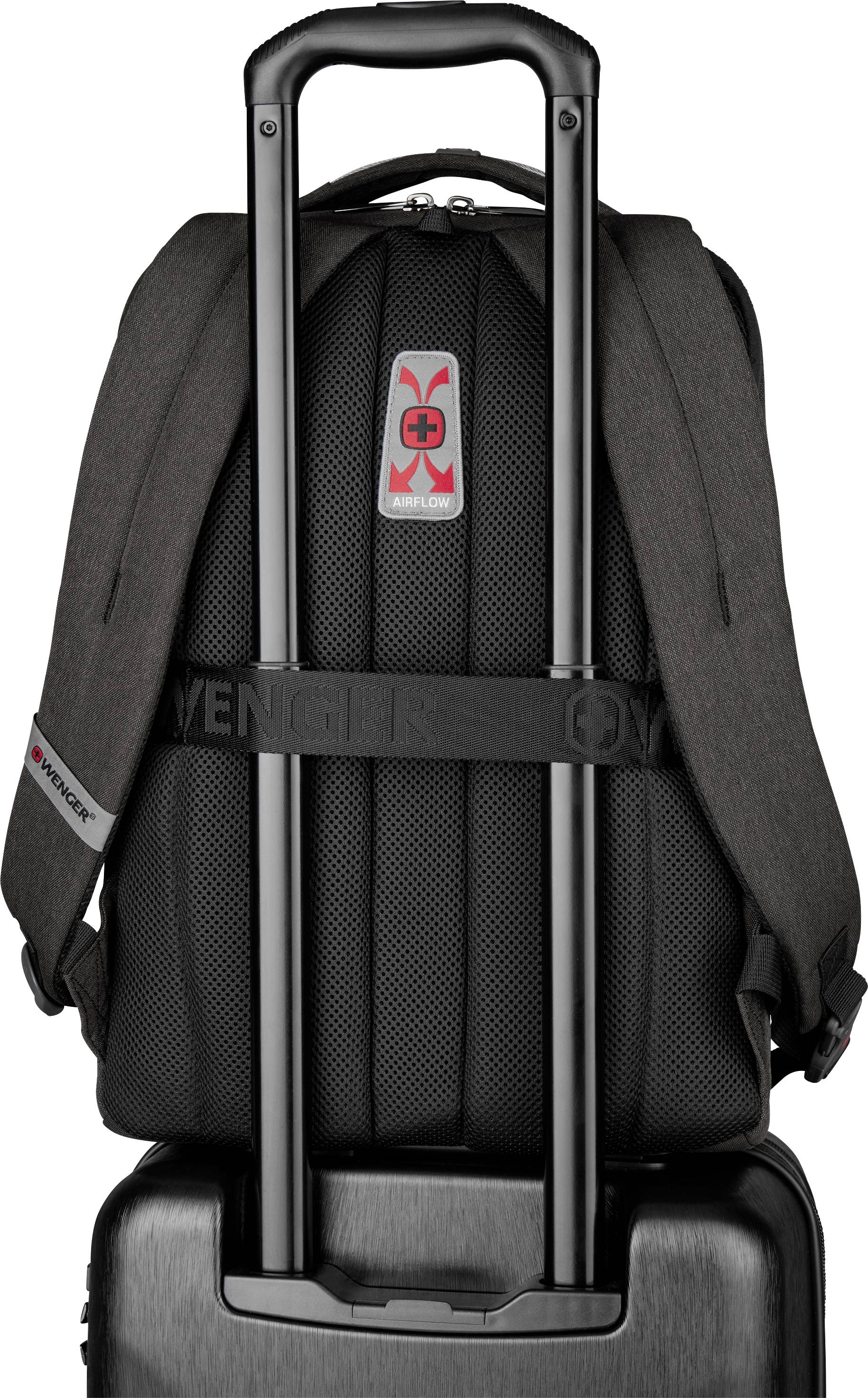 Travel rucksack made of sturdy fabric, suitcase's telescopic handle threaded through the loop, brand logo visible at the top.