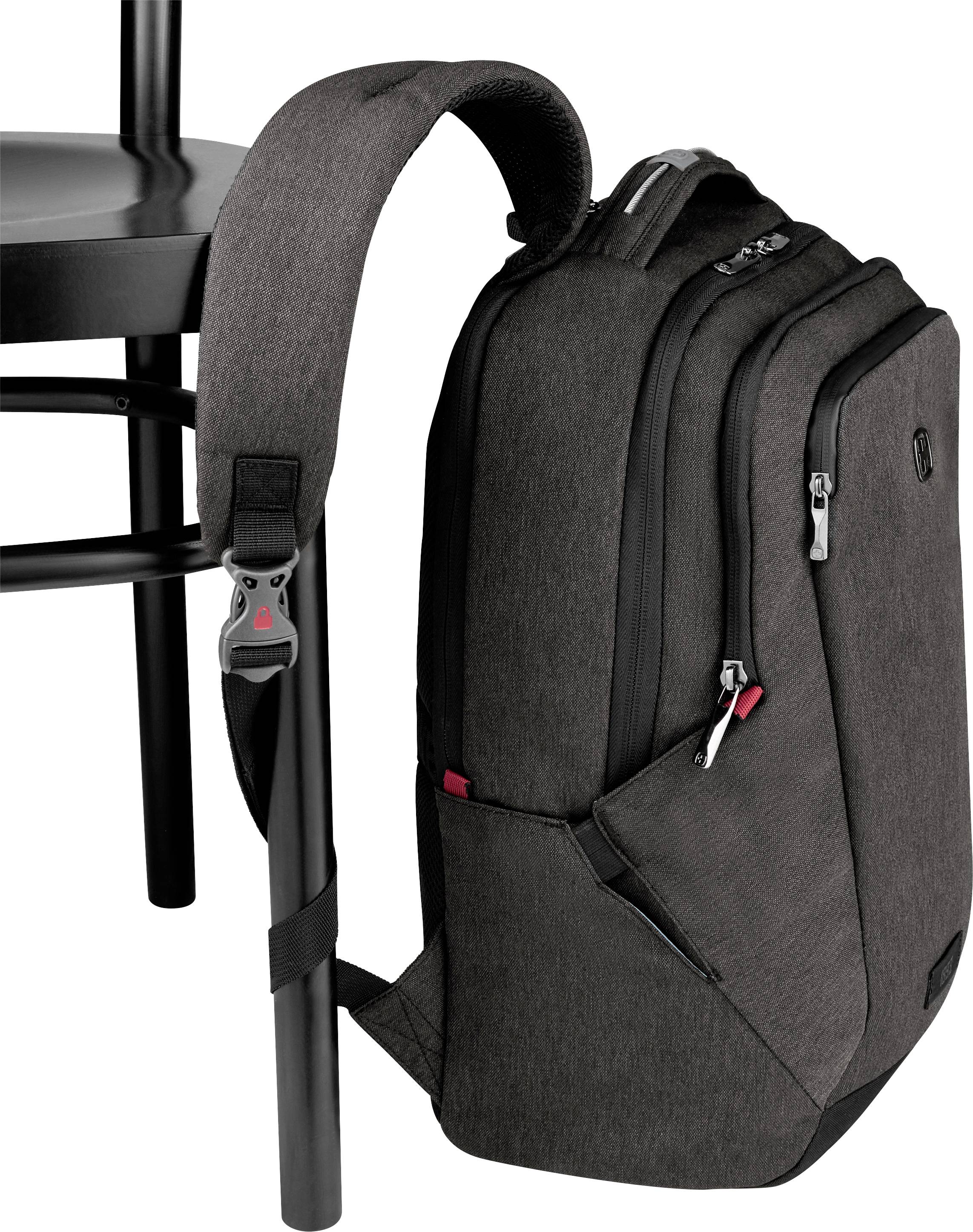 A black rucksack is securely hanging on a chair, fastened with an integrated strap.