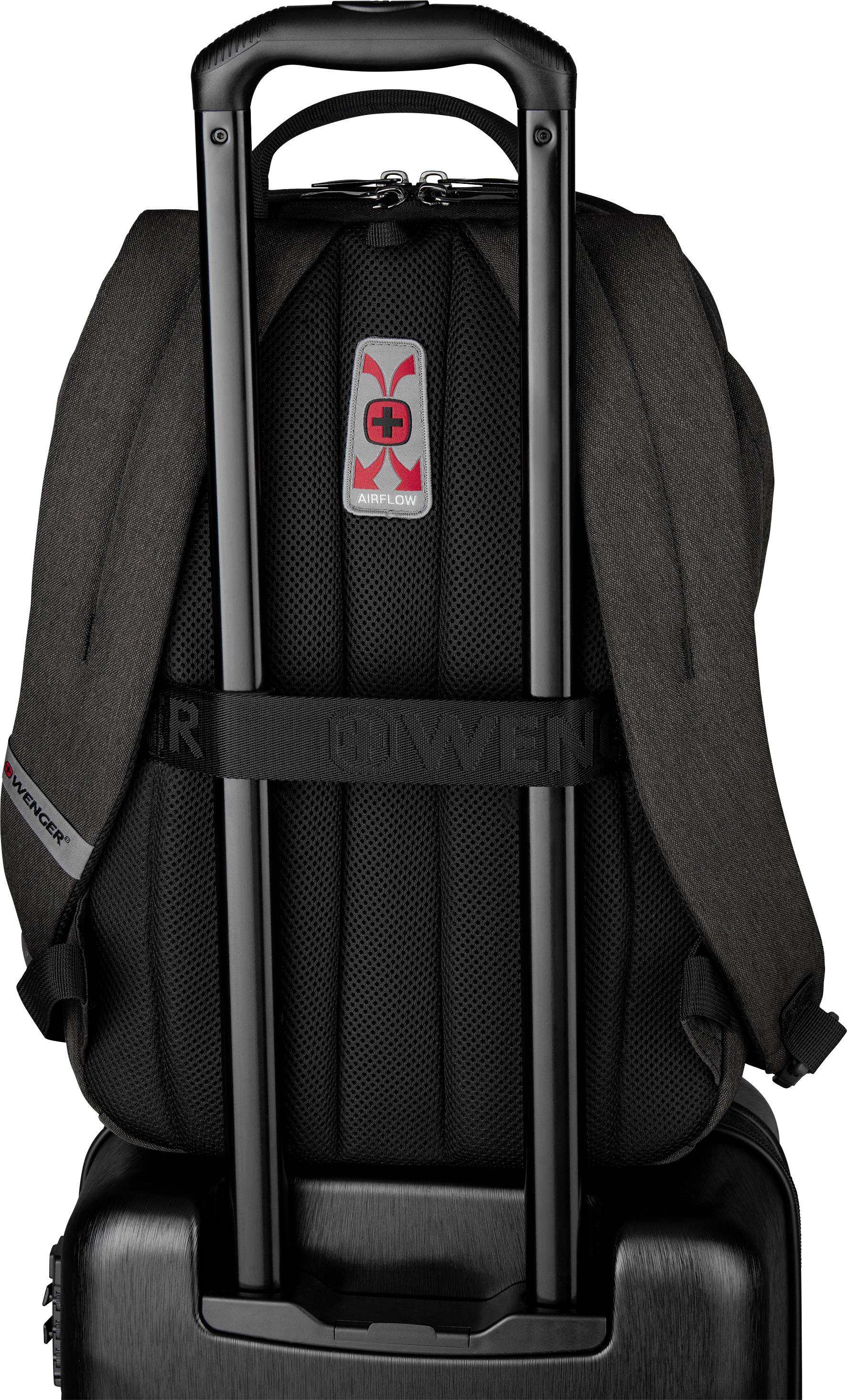 A rucksack is pushed through the handles of a travel suitcase. The rucksack is black with a red and white logo.