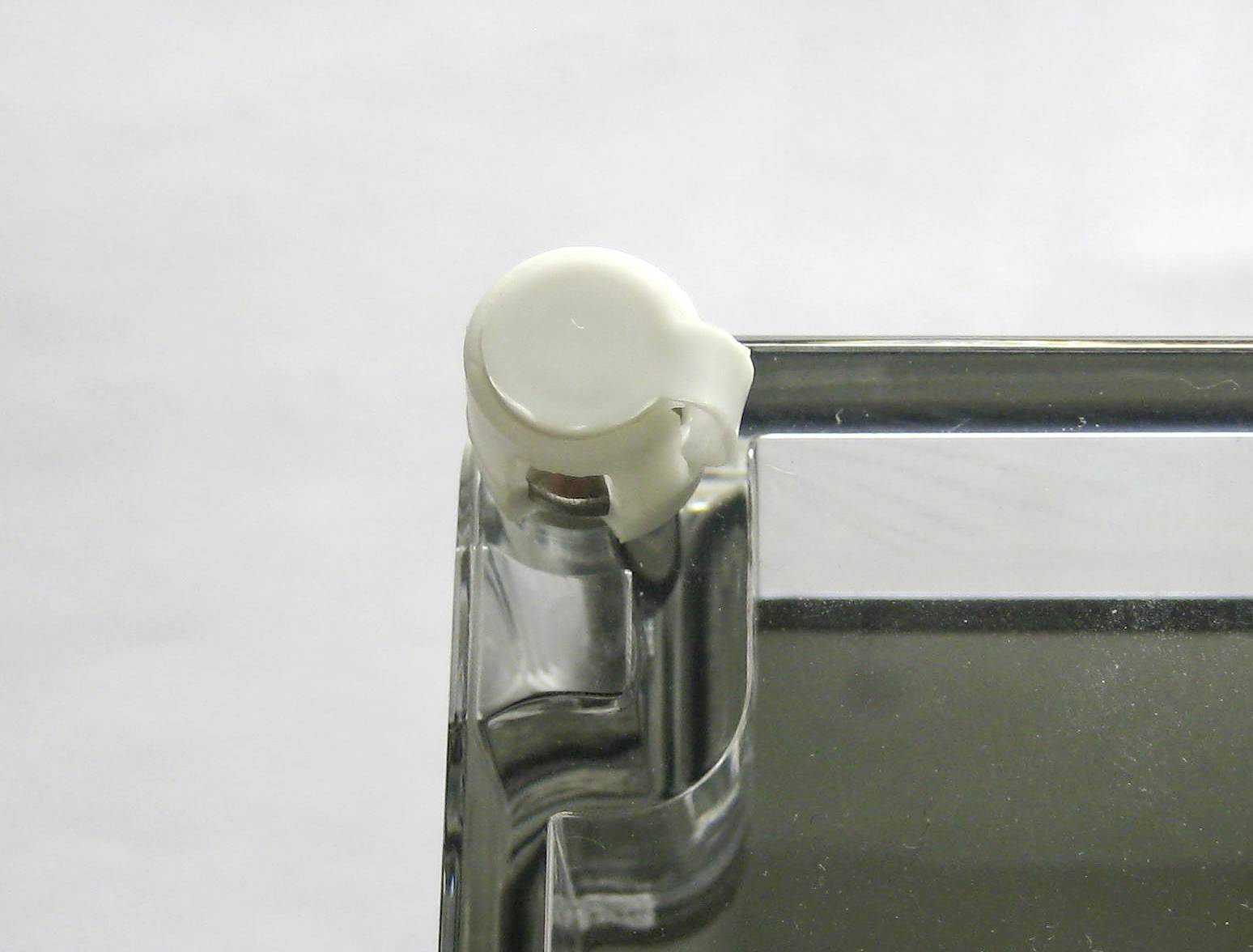 Glass plate with a white plastic attachment at one corner, showing a detail of a piece of furniture or building material.