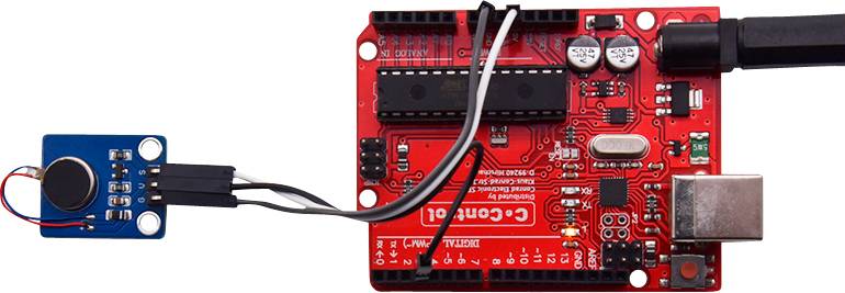 Red circuit board of the Arduino microcontroller, connected to a smaller blue sensor. USB cable connected on the right.