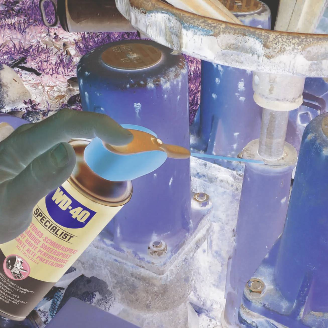 A blue-gloved hand uses WD-40 spray on a rusty metal valve, aiming to loosen or protect it from corrosion in an industrial setting.