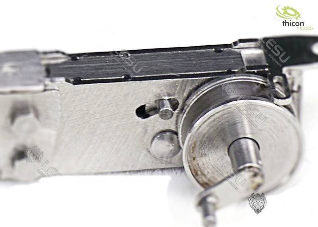 Close-up of a metallic gear or machine component. Visible are gears and metal connecting pieces on a white background.