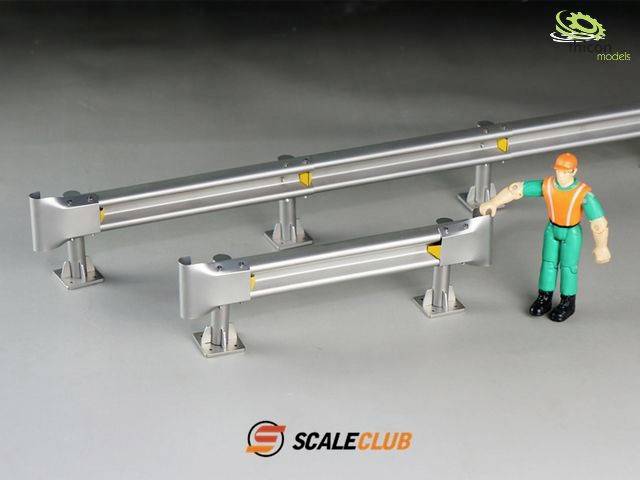 A figure in orange and green clothing stands next to two miniature crash barriers on a grey surface, with the logo 'SCALECLUB'.
