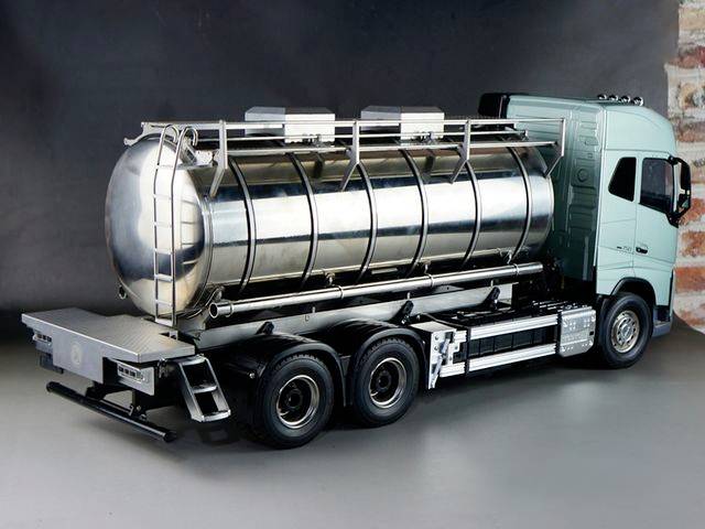 Silver tanker lorry on a grey background, ready for liquid transportation. It has six wheels and a turquoise driver's cab.