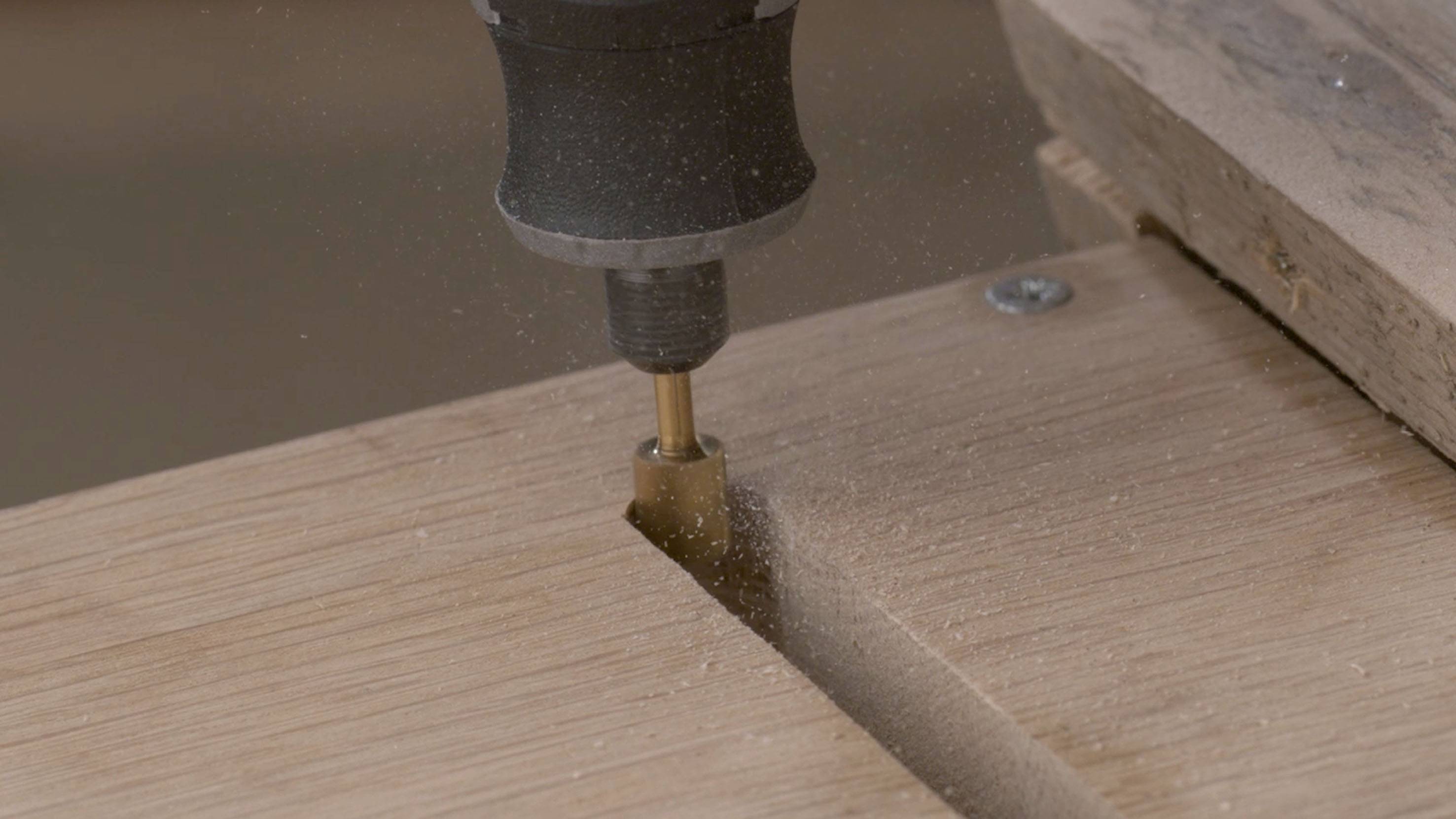 Close-up of a milling machine processing a wooden board, producing wood shavings.