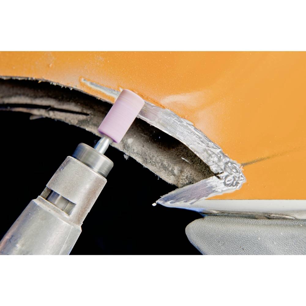 Close-up of a grinding machine removing metal from an orange surface; demonstrates the metalworking process.