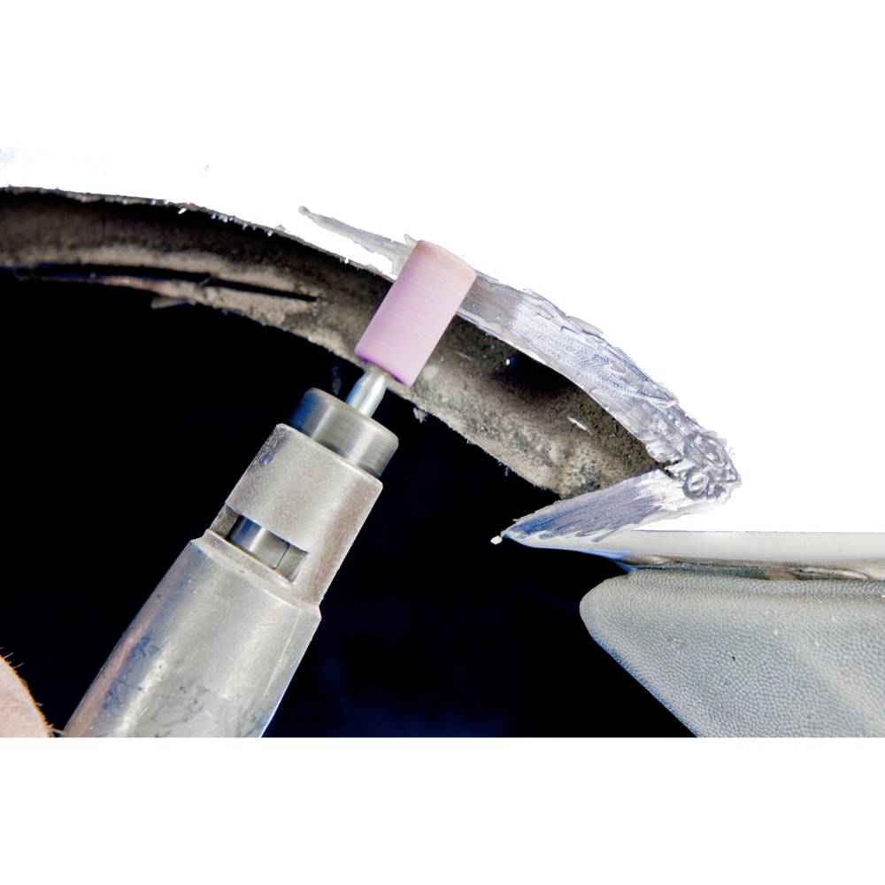 A drill with a grinding attachment is machining a metal surface, polishing a section of the edge.