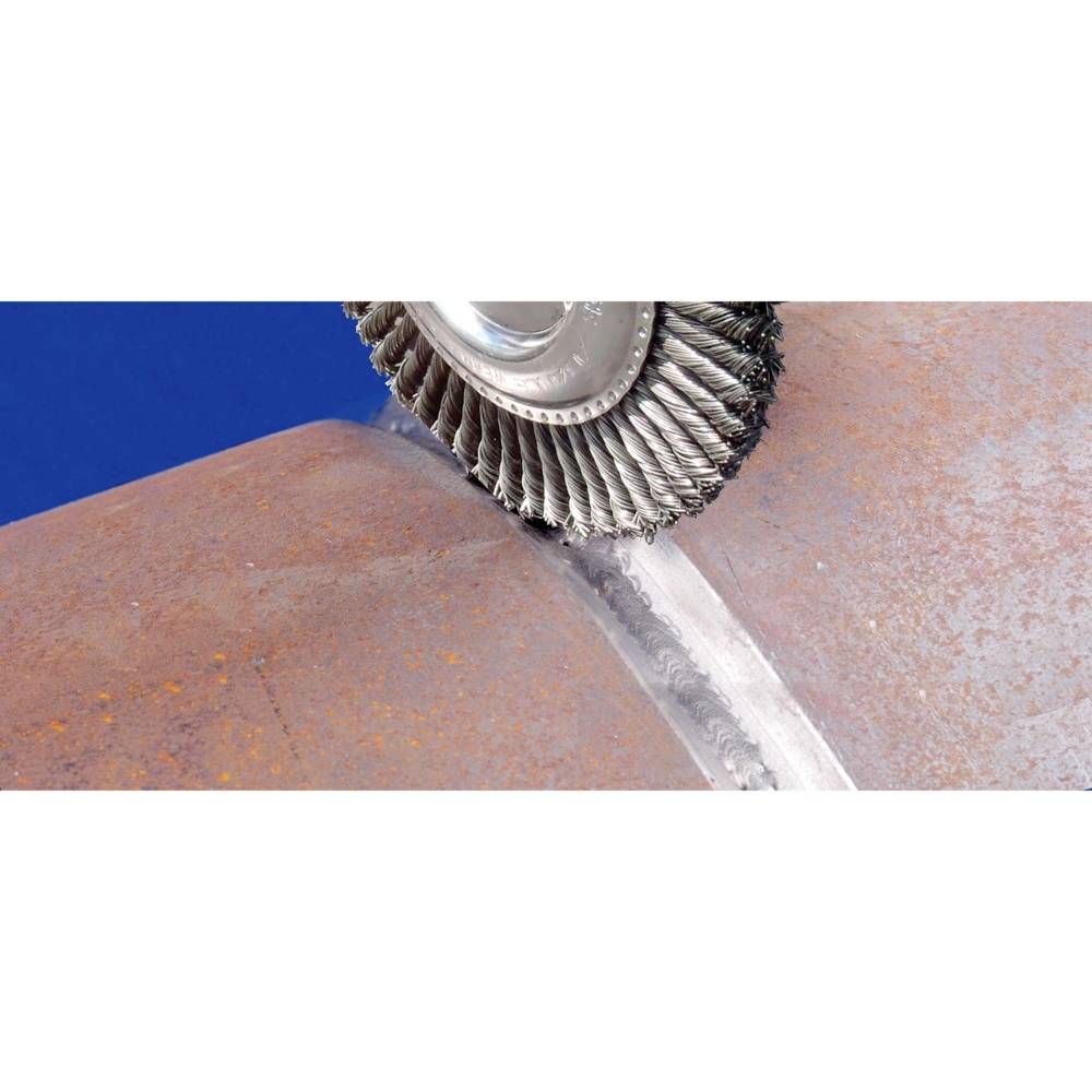 A grinding tool polishes the weld joint between two pipes. The tool has rotating bristles. The pipes are rust-coloured.