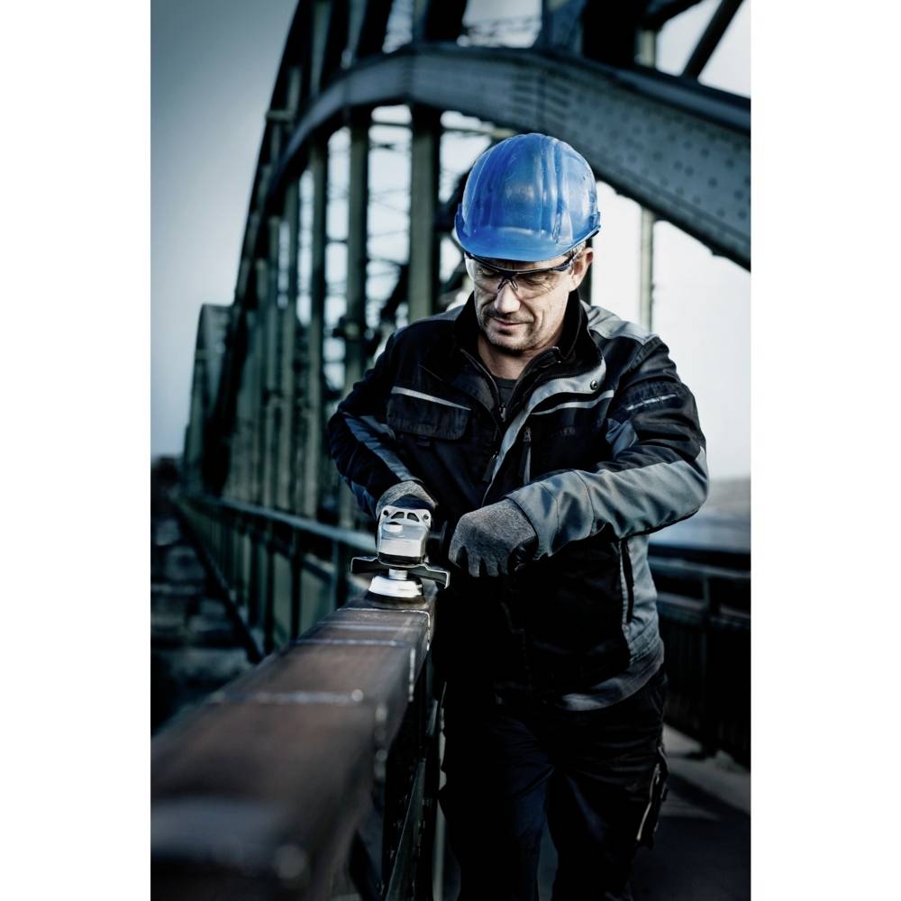 A construction worker wearing a blue hard hat is taking measurements with a device on a bridge. The background shows the steel bridge construction.