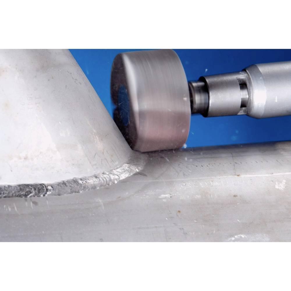 A machine is machining the corner of a metal piece. A knife or head is touching the edge to shape or smooth the material.