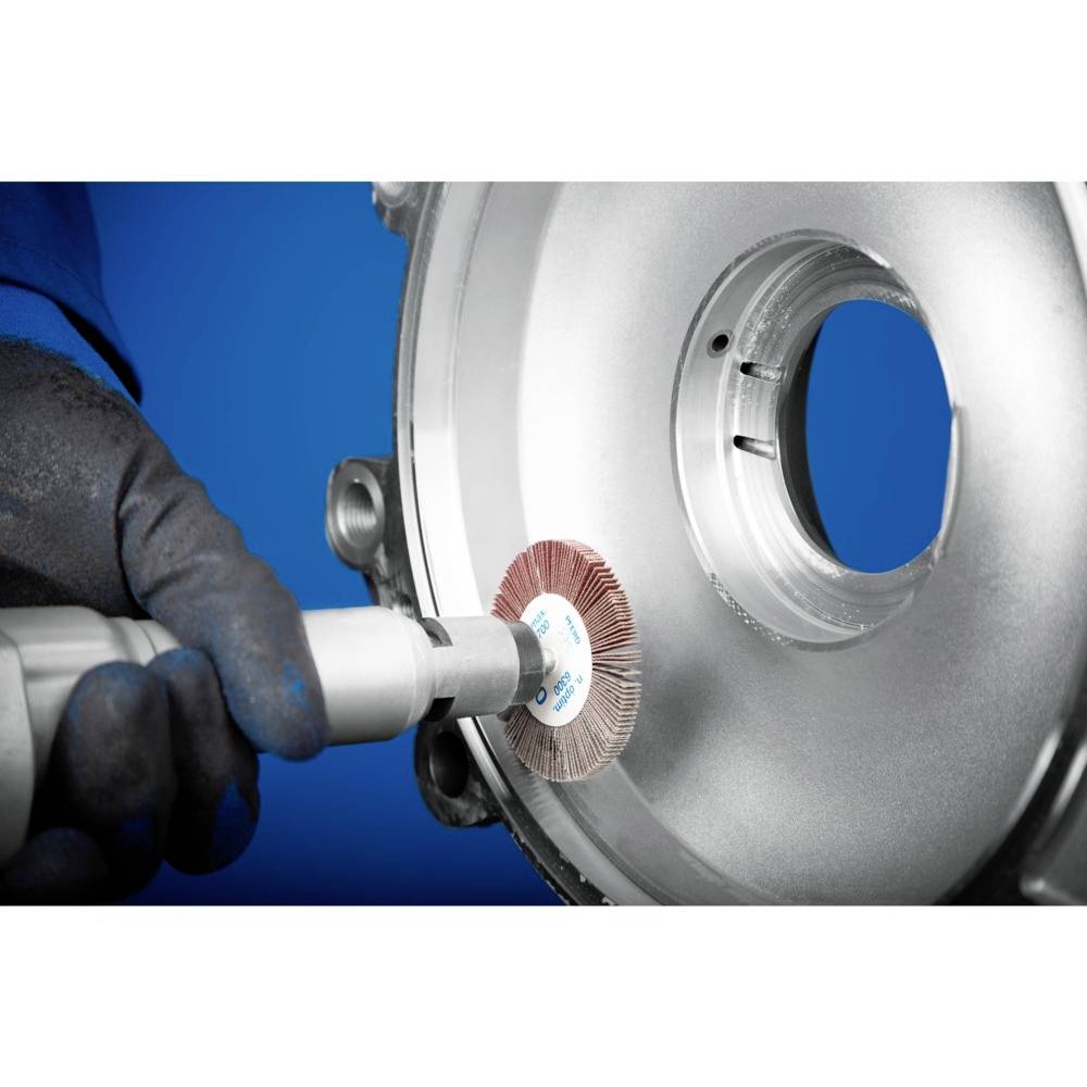 A hand wearing a protective glove is holding an electrical device that uses a rotating metal brush to polish the surface of a metal component.