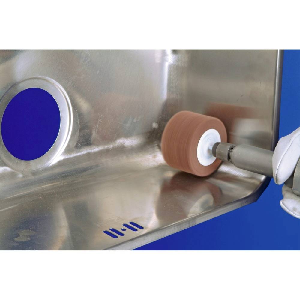 A polished metal surface is being processed with a rotating grinding tool, with a circular opening visible beside it.