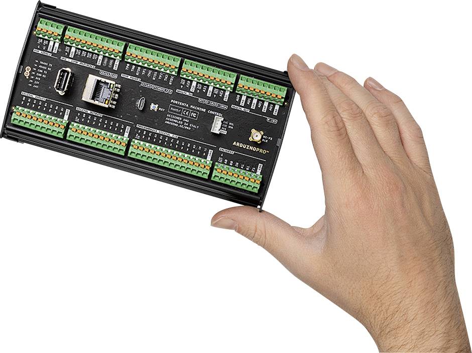 A hand is holding an electronic control unit with multiple ports and components.