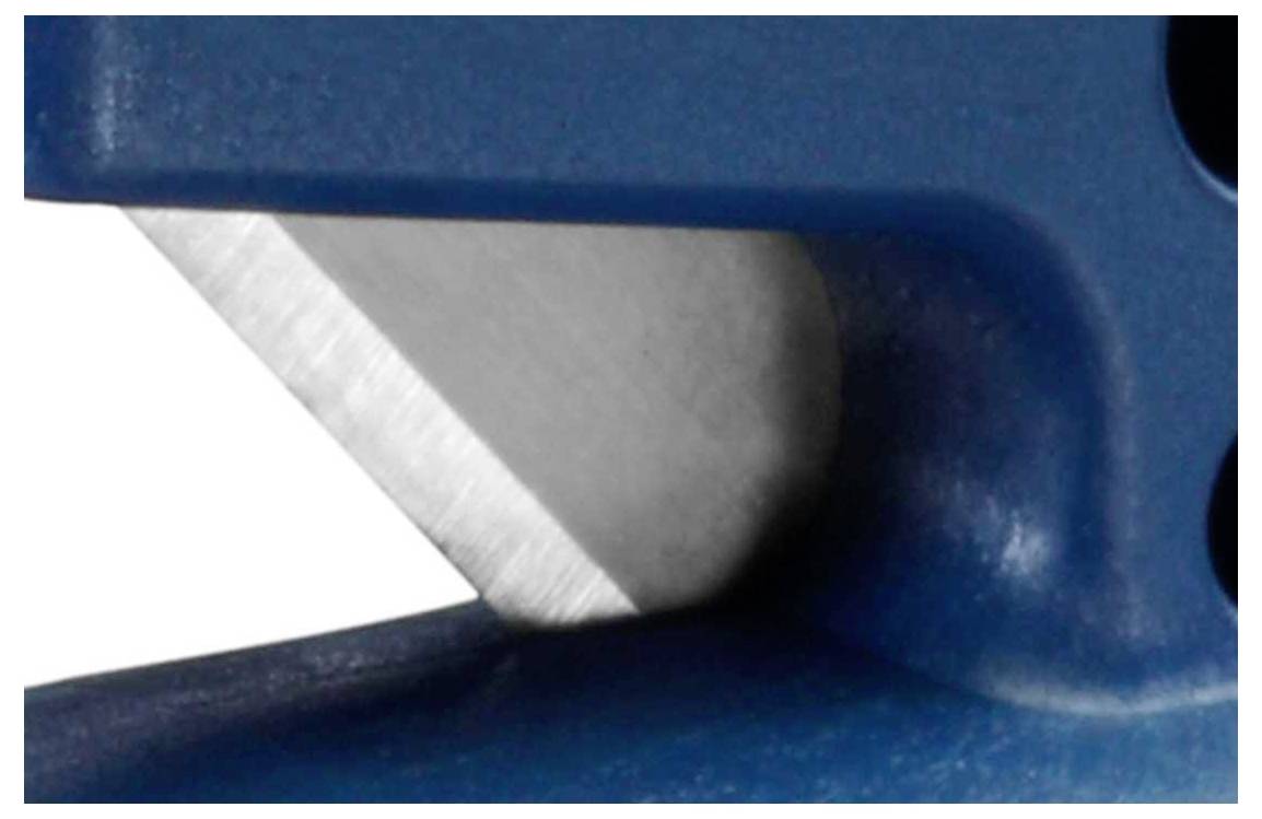 Close-up of a blue, metallic tool with a sharp edge.