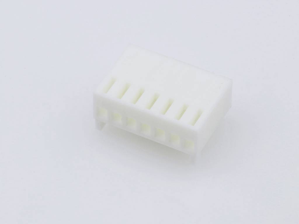 A white plastic plug with multiple connection openings, lying on a white surface.