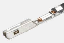 Close-up of a metal plug with grooves and copper wires attached at the ends.