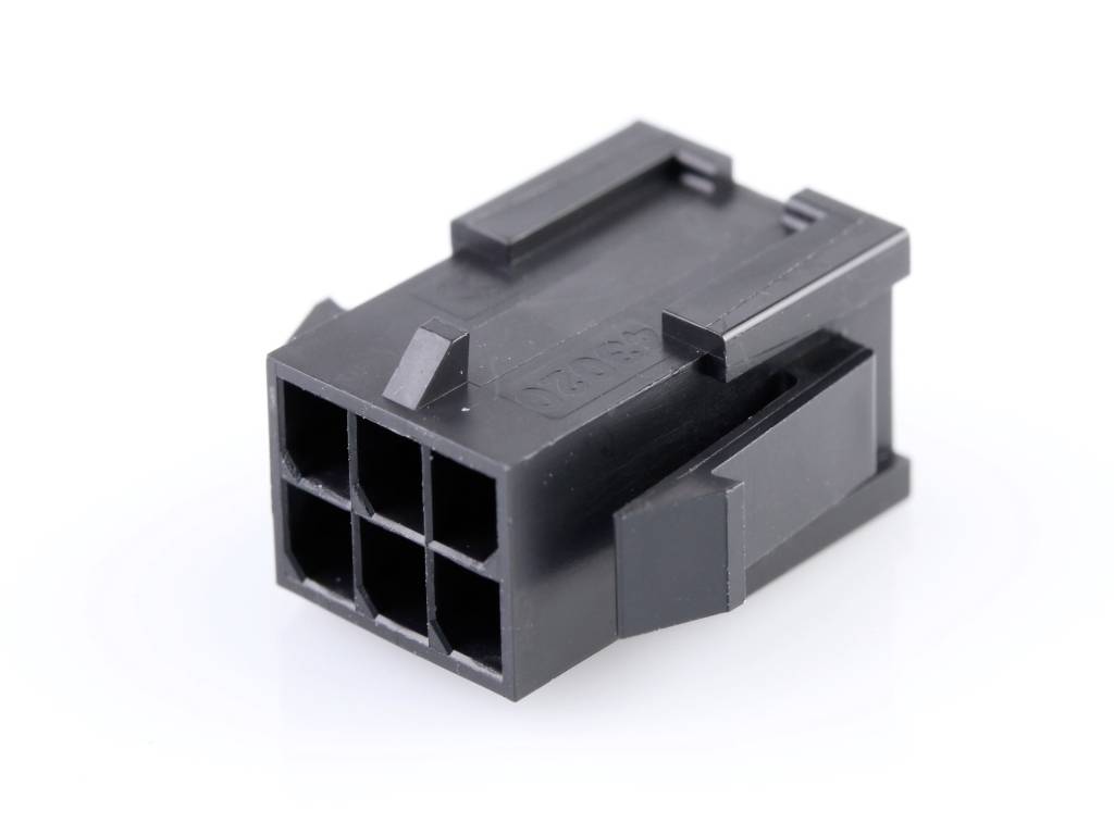 A black, six-pole electrical plug housing adapter is lying on a white surface.