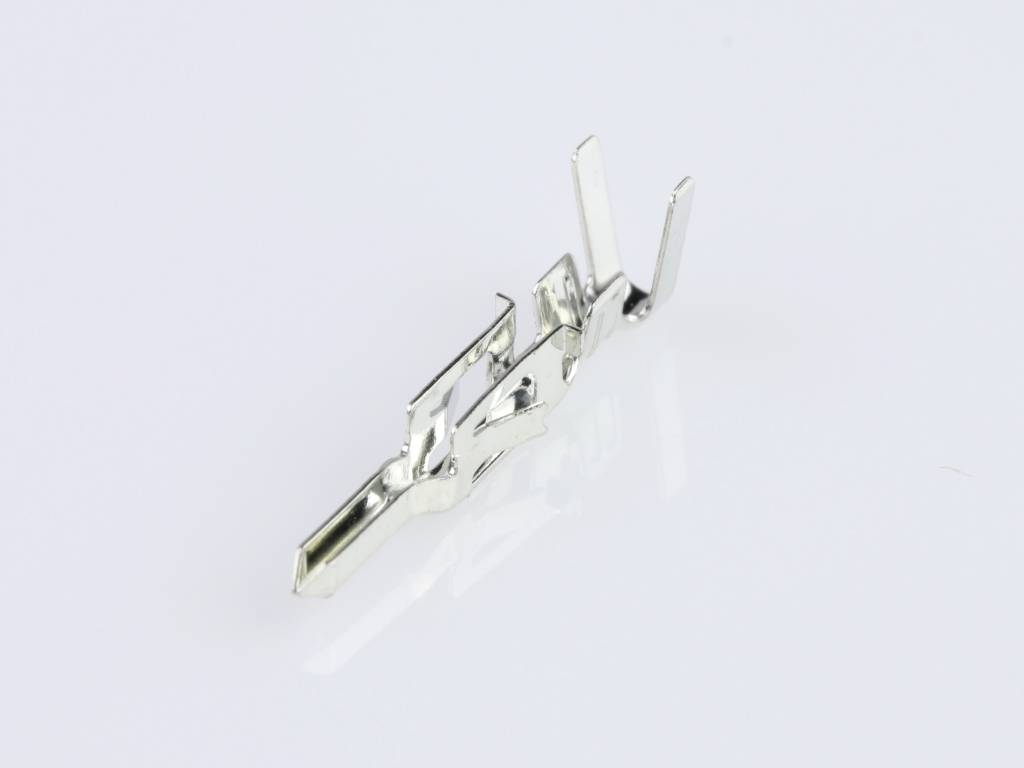 A silver metal component lying flat on a shiny surface. It has several angles and edges, possibly a connector.