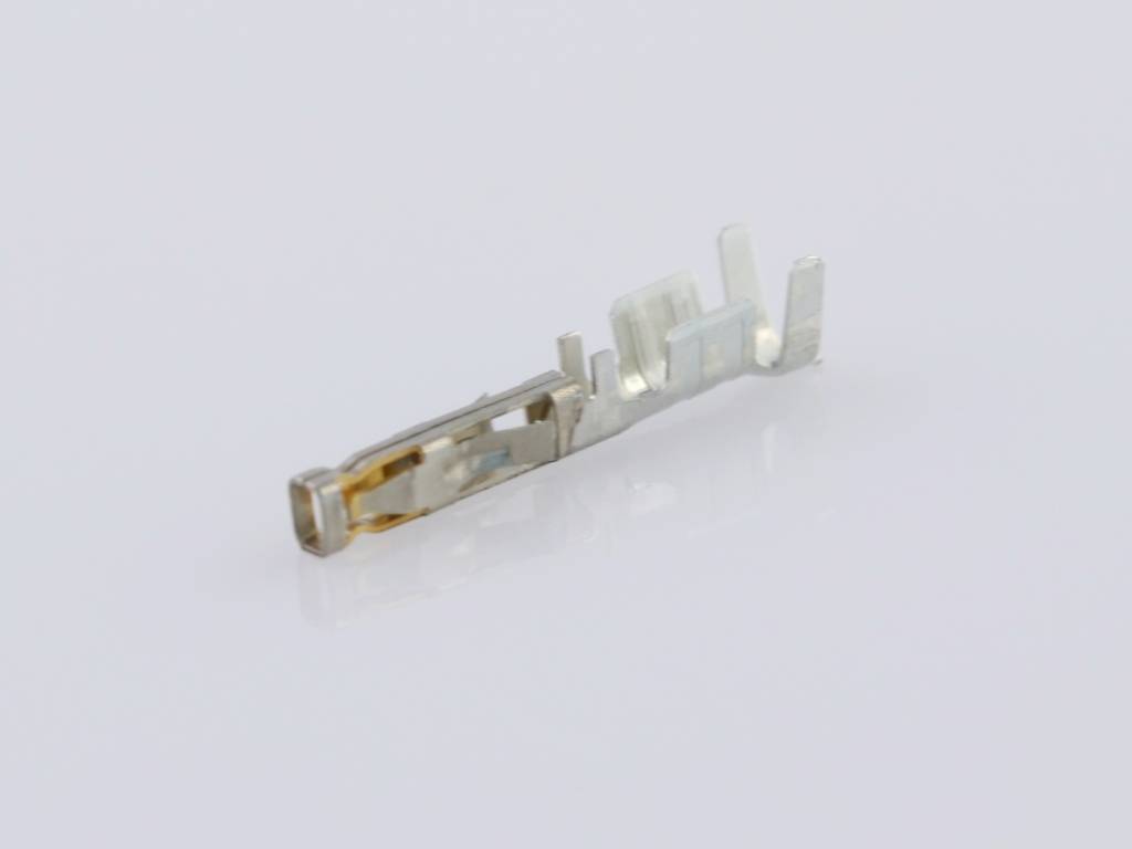A single, silver-coloured connector contact lies on a white surface.