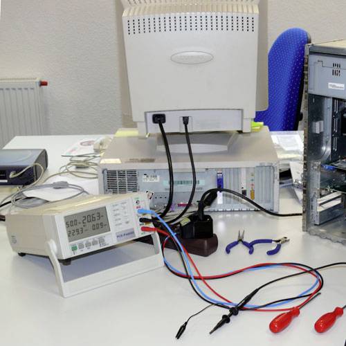In a laboratory, an open computer sits on a table with connected electronic measuring instruments and tools.