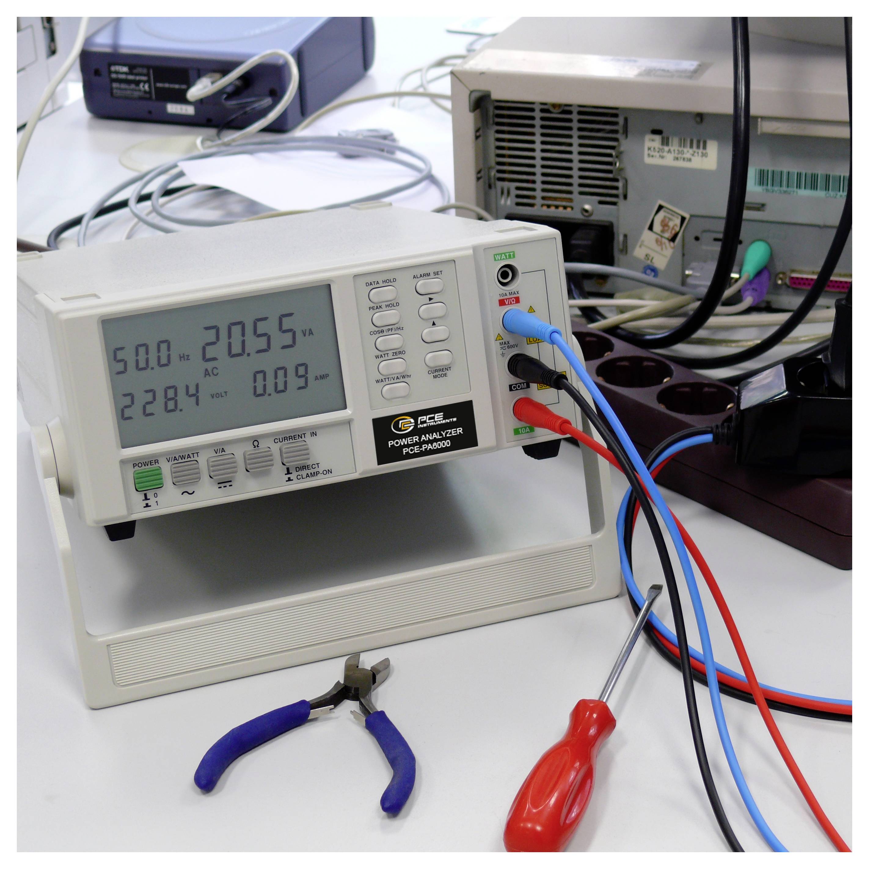 Benchtop power analyzer displays electrical readings while red, blue, and black test leads connect to nearby equipment.