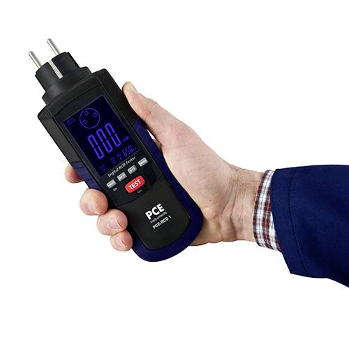 Measuring device for measuring current and voltage. One hand is holding the device. Display shows 