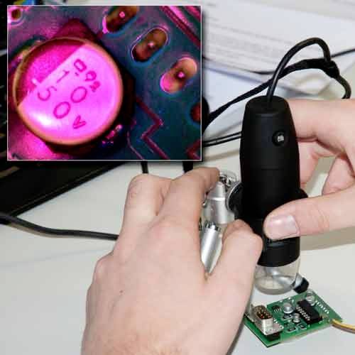 A person is examining electronic components under a microscope. A close-up shot reveals numbers on a capacitor.